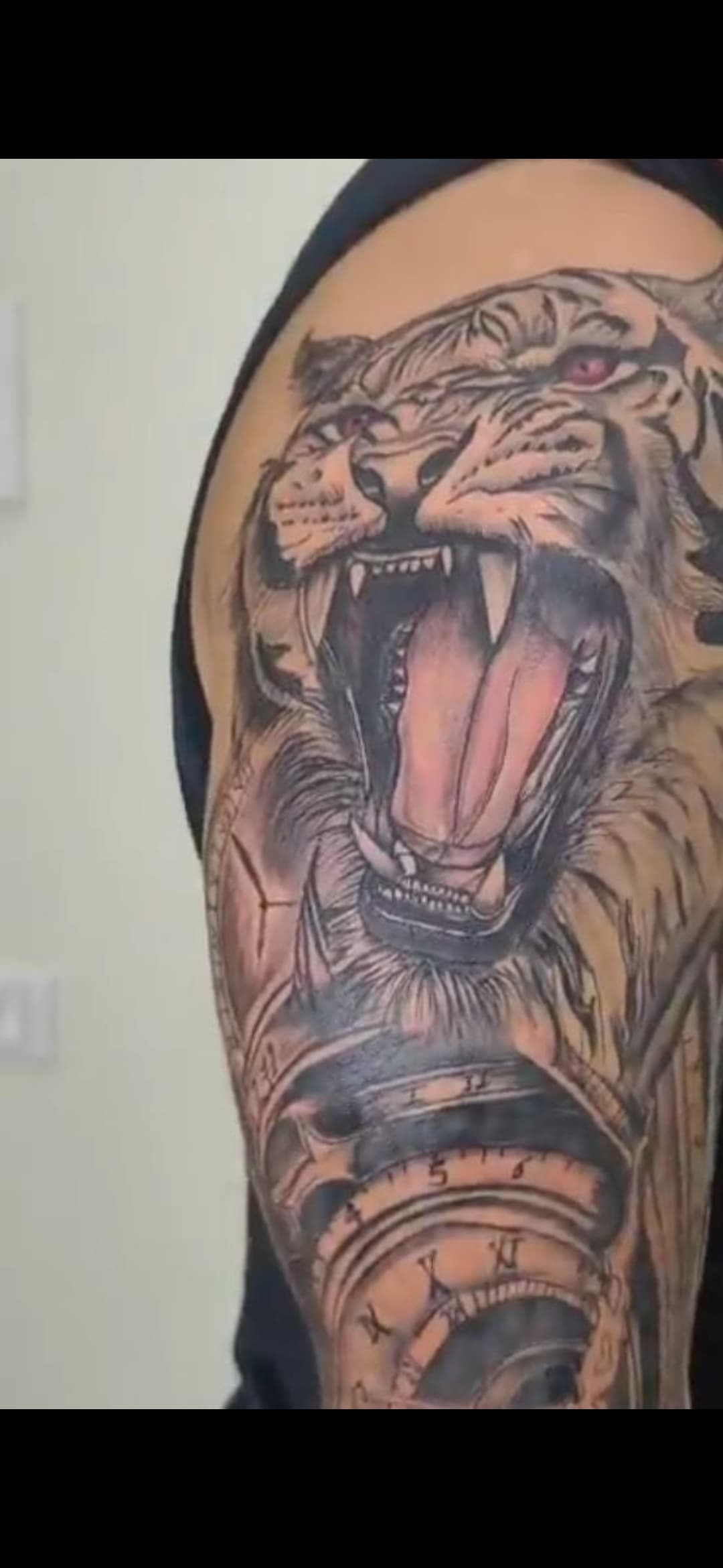 Detailed tattoo of a roaring tiger with red eyes above a clock with Roman numerals.